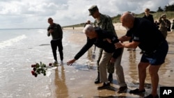 Bill Wall, veteran american din al Doilea Război Mondial, aruncă trandafiri în ocean în timpul unei ceremonii de depunere de coroane pe plaja Utah Beach - 5 iunie 2024.