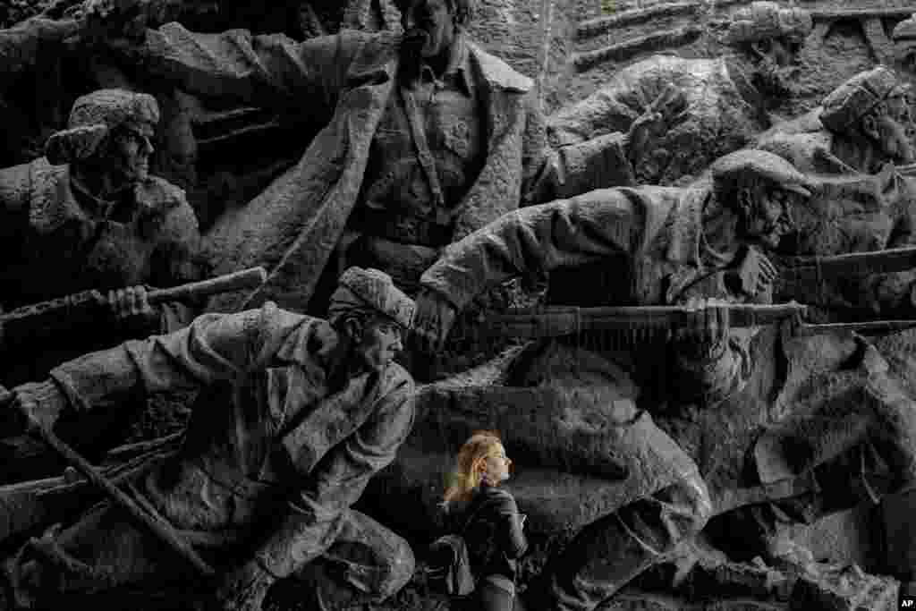 A woman walks by bas-relief sculptures depicting war scenes in the National Museum of the History of Ukraine in the Second World War in Kyiv.