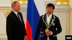 Russian President Vladimir Putin (left) and one of the country's Olympic gold-medal winners, judoka Beslan Mudranov, attend a ceremony for Russian Olympic medalists at the Kremlin on August 25.