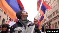 Протестующий несет армянский флаг на демонстрации в Ереване. 