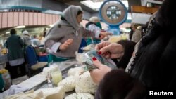 Покупательница у прилавка с молочной продукцией на рынке в Алматы. 