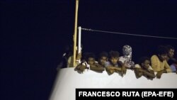 Tineri migranți așteptînd să fie debarcați de pe nava Frontext, 'Protector', în portul Pozzallo, Sicilia