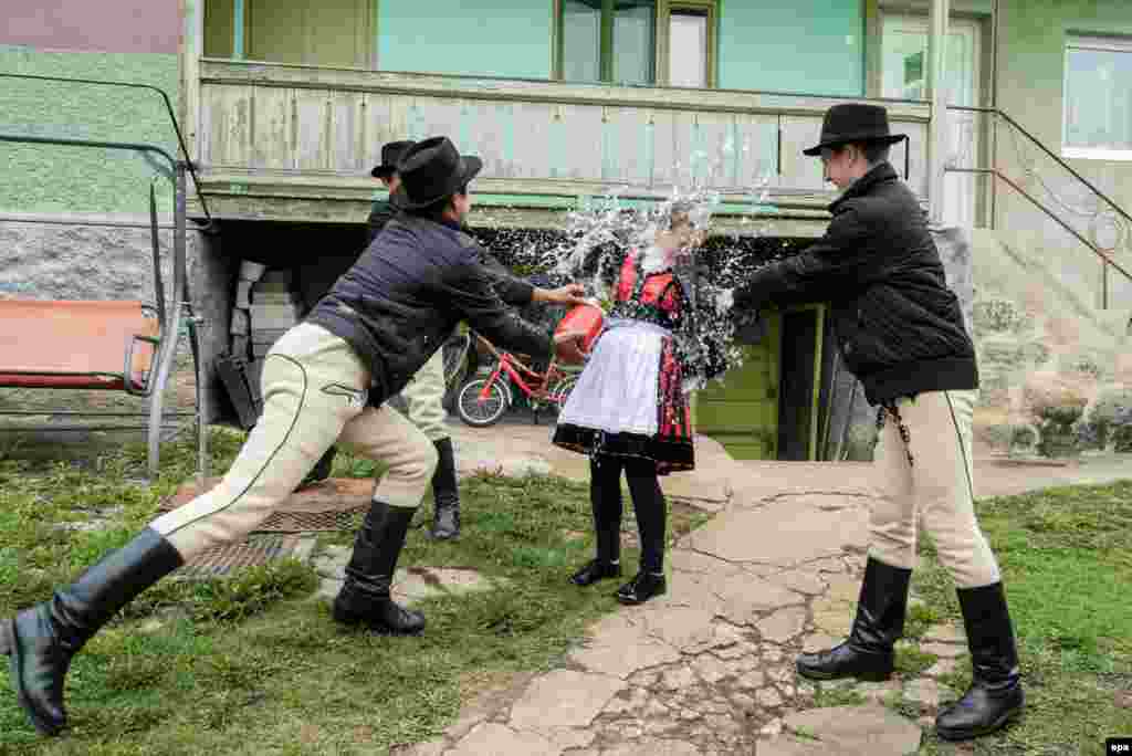A group of ethnic Hungarian young men dressed in folk costumes splash water on a girl in the Transylvanian village of Csikmindszent, or Misentea in Romanian. According to an old Hungarian tradition, young men pour water on young women on Easter Monday. The women in exchange present their "sprinklers" with hand-decorated hens' eggs. (epa/Nandor Veres)