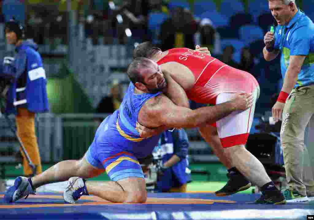 Levan Berianidze of Armenia (in blue) in action against Ibrahim Saidau of Belarus during the men's freestyle wrestling 125-kilogram-bronze medal bout. Turkey's Taha Akgul won gold, with Ghasemi taking silver, and Saidau and Geno Petriashvili of Georgia sharing the bronze.