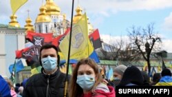 Молоді люди у захисних масках на акції у День українського добровольця біля Михайлівського собору в Києві, що належить ПЦУ, 14 березня 2020 року