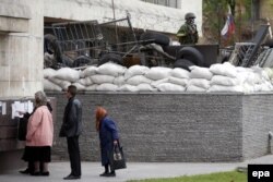 Ресейшіл сепаратистер басып алған облыстық әкімшілік жанында референдум туралы хабарландыру оқып тұрған адамдар. Донецк, 9 мамыр 2014 жыл.