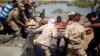 A wounded displaced man is evacuated by Iraqi forces across the Tigris.