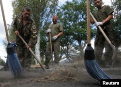 Militari din forțele guvernamentale, capturați de separatiști, curăță o stradă în Snijne, lângă Donețk, 29 august, 2014
