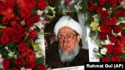 The portrait of former Afghan President Sibghatullah Mojaddedi is seen in the wreath of flowers during his funeral procession at the presidential palace in Kabul, February 13, 2019