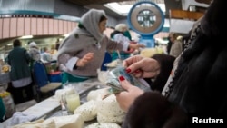 A woman counts out several tenge banknotes while purchasing some dairy products at a market in Almaty. The declining value of the Kazakh currency has hit the country's economy hard and some believe the worst is yet to come. 