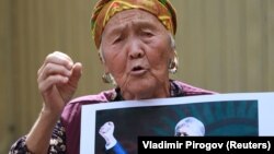 Gyrgyzystanyň öňki prezidenti Almazbek Atambaýewiň tarapdarlarynyp biri ýurduň Milli Howpsuzlyk boýunça döwlet komitetiniň binasynyň golaýynda çykyş edýär. 16-njy awgust, 2019 ý.