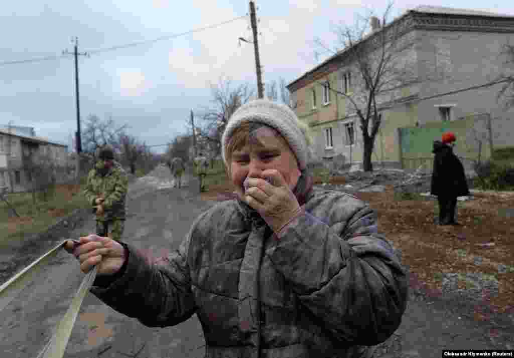 Жінка плаче біля свого будинку, який був пошкоджений під час обстрілу, здійсненого російськими гібридними силами з реактивної системи залпового вогню &laquo;Град&raquo; по населеному пункту Новолуганське на Донеччині,&nbsp; 19 грудня 2017 року