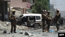 Afghan security forces stand guard near a damaged vehicle at the site of a suicide bombing that targeted NATO forces in Kabul on July 7.