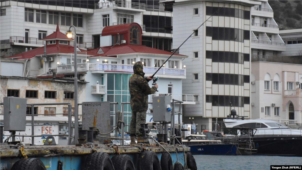 Чоловік за допомогою спінінга рибалить із пристані
