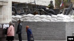 Ukrainians read referendum materials in the eastern city of Donetsk as a supporter of the self-declared Donetsk People's Republic stands guard outside the seized regional administration building on May 9, two days ahead of the planned vote.