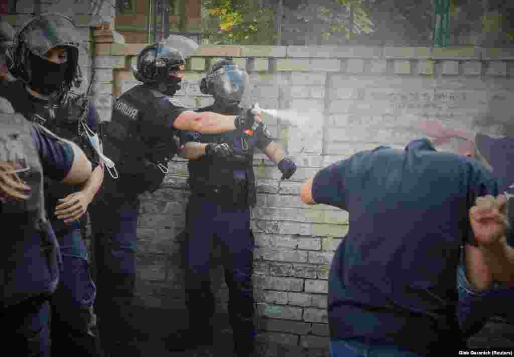 Ukrainian police officers use pepper spray to restrain anti-LGBT protesters attempting to disrupt a pride rally near the headquarters of the presidential office in Kyiv on July 30.&nbsp;