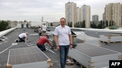Muncitori ucraineni instalează panouri solare pe acoperișul unui spital din Kiev, în timpul unei pene de curent, pe 14 iunie 2024, după un nou atac rusesc asupra intalațiilor energetice din Ucraina.