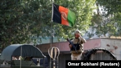 AFGHANISTAN -- Security force member stands over a military car before leaving the site of a suicide attack followed by a clash between Afghan forces and insurgents after an attack on Iraq embassy in Kabul, Afghanistan, July 31, 2017. 