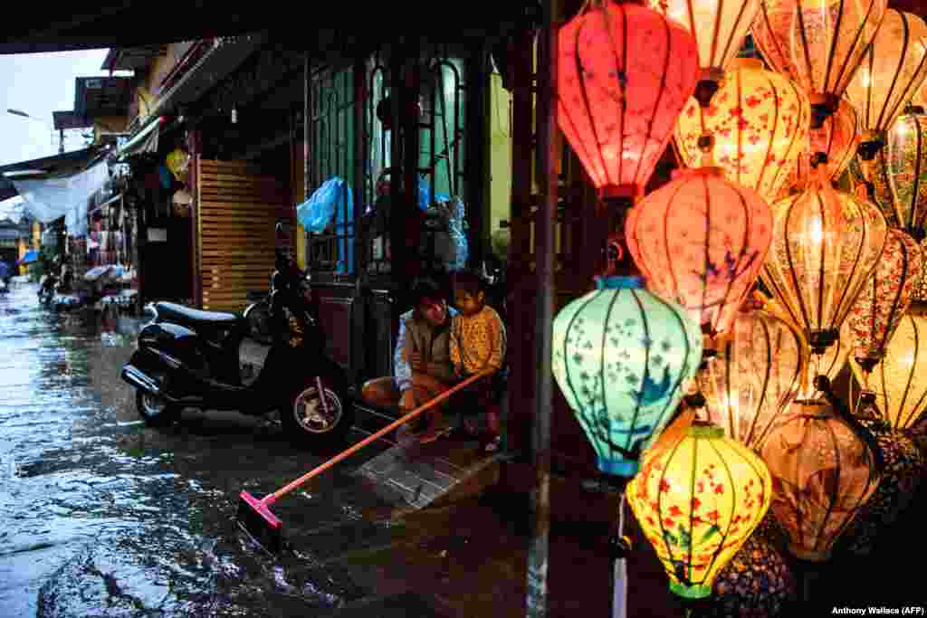 A mother and her child sit next to a lantern shop in the Vietnamese town of Hoi An on November 8 following days of heavy rains after Typhoon Damrey hit the coast. (AFP/Anthony Wallace)