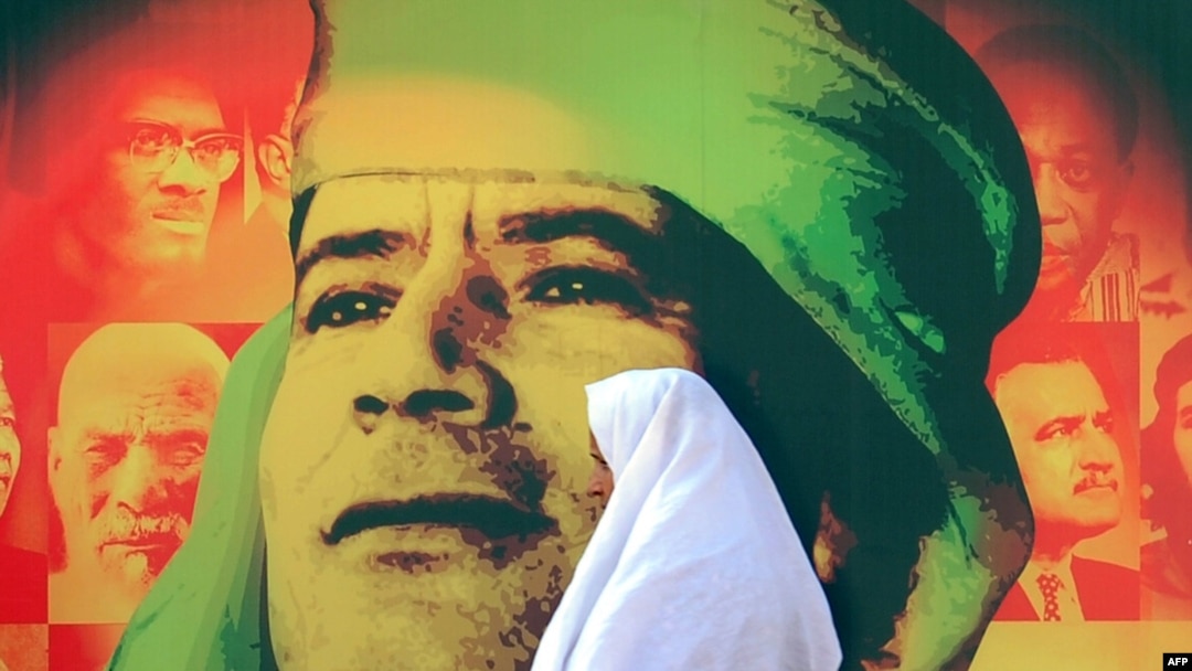 A woman walks past a picture of Libyan leader Muammar Qaddafi in Tripoli.