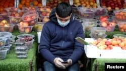 Čovjek sa zaštitnom maskom čeka mušterije na pijaci u Birminghamu, Velika Britanija, 30. part, 2020. 