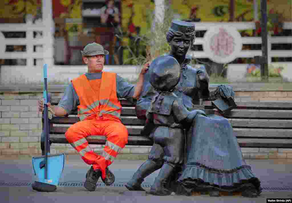 A municipal worker sits on a bench next to a statue in Nizhny Novgorod, Russia, during the 2018 soccer World Cup. (AP/Vadim Ghirda)