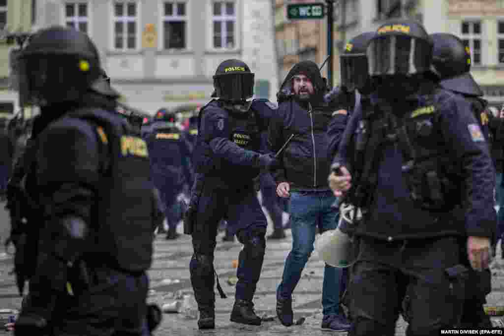 Riot police detain a protester as hundreds of demonstrators, mostly hooligans, protest against the Czech government's new measures in connection with the COVID-19 pandemic caused by the SARS-CoV-2 coronavirus, at the Old Town Square in Prague, Czech Republic, 18 October 2020. 