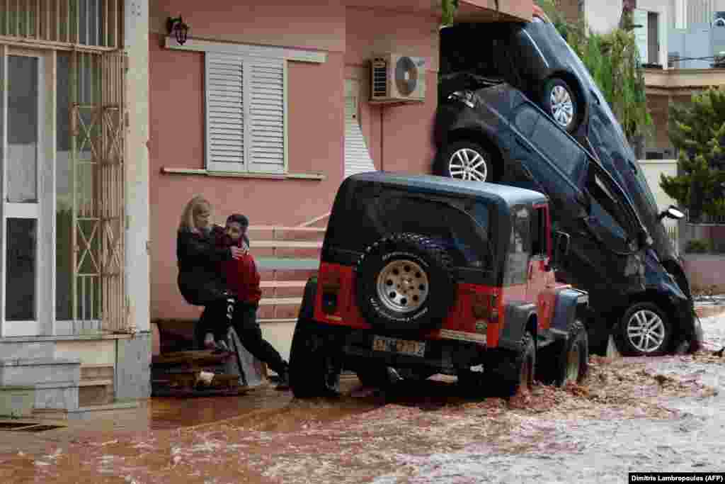 ГРЦИЈА - Маж и помага на жена да ја премине поплавената улица во градот Мандра, во близина на Атина, по големите поплави и невремето што ја зафатија Атика. Седумнаесет лица досега настрадаа од поплавите во грчката област Атика, говорат последните официјални информации. Пожарникарите бараат шест исчезнати лица, објавија локалните медиуми.