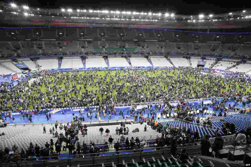 Stade de France стадионына Германия мен Франция ұлттық футбол құрамаларының жолдастық кездесуін тамашалауға келгендер матч кезінде бірнеше жарылыс естілген соң ойын алаңына жиналды. Париж, 13 қараша 2015 жыл.