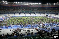 Зрители ждут разрешения на выход со стадиона Stade de France в Париже после серии взрывов в пятницу, 13 ноября
