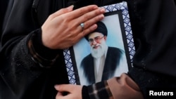 Жінка тримає фотографію Верховного лідера Ірану аятоли Алі Хаменеї на площі Енгелаб після того, як він був убитий внаслідок ізраїльських та американських ударів у суботу, в Тегерані, Іран, 1 березня 2026 року