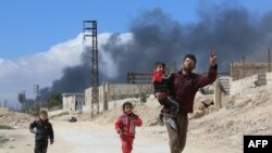 Syrians from the rebel-held eastern Ghouta region, just outside Damascus, walk through a regime-controlled corridor in Hamuria on March 16.