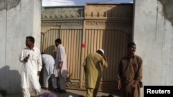 Local residents on May 4 try to look past the gates into the compound where Al-Qaeda leader Osama bin Laden was killed in Abbottabad, Pakistan.