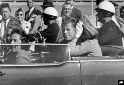 Presidenti John F.Kennedy duke përshëndetur qytetarët nga vetura e tij, pothuajse një minutë para se të qëllohej për vdekje më 22 nëntor 1963.