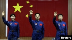 Chinese astronauts Jing Haipeng (center), Liu Wang (right), and Liu Yang, China's first female astronaut, wave to the media during a news conference at Jiuquan Satellite Launch Center, in Gansu Province, on June 15.