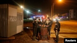 Crimean Tatars with a "self-preservation" patrol warm themselves around a fire on a night shift on the outskirts of Simferopol.