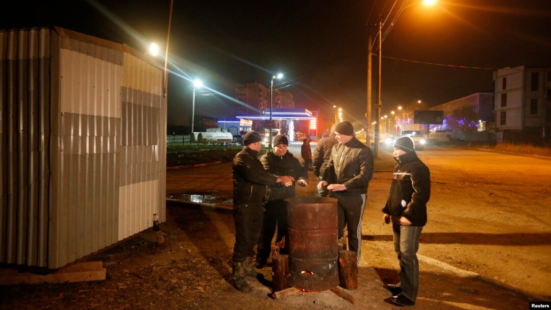 Crimean Tatars with a "self-preservation" patrol warm themselves around a fire on a night shift on the outskirts of Simferopol. 