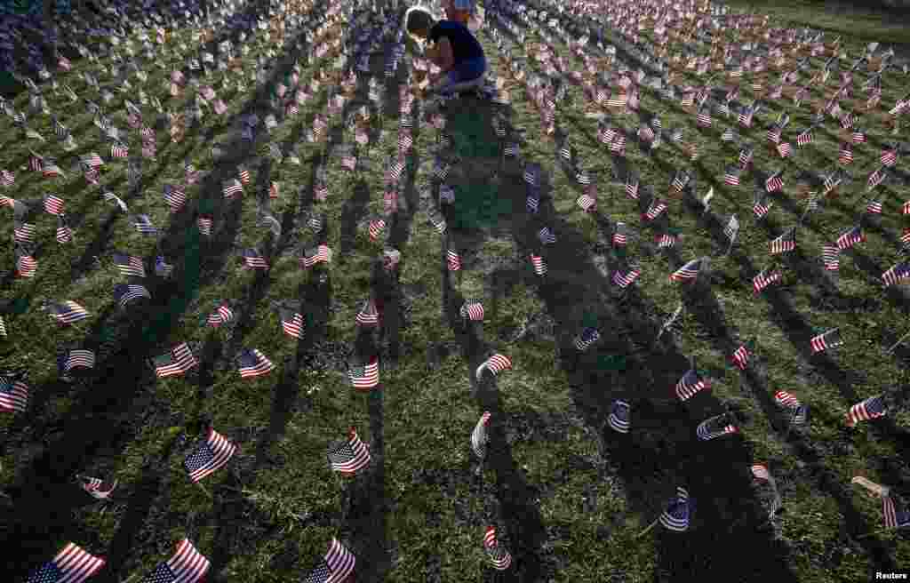 A girl plants some of the 3,000 flags placed in memory of the lives lost in the September 11, 2001 attacks at a park in Winnetka, Illinois. (Reuters/Jim Young)