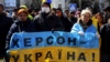 People hold a Ukrainian flag with a sign that reads "Kherson is Ukraine" during a rally against the Russian occupation in Kherson on March 20.