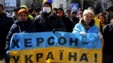 People hold a Ukrainian flag with a sign that reads "Kherson is Ukraine" during a rally against the Russian occupation in Kherson on March 20.