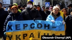 People hold a Ukrainian flag with a sign that reads "Kherson is Ukraine" during a rally against the Russian occupation in Kherson on March 20.