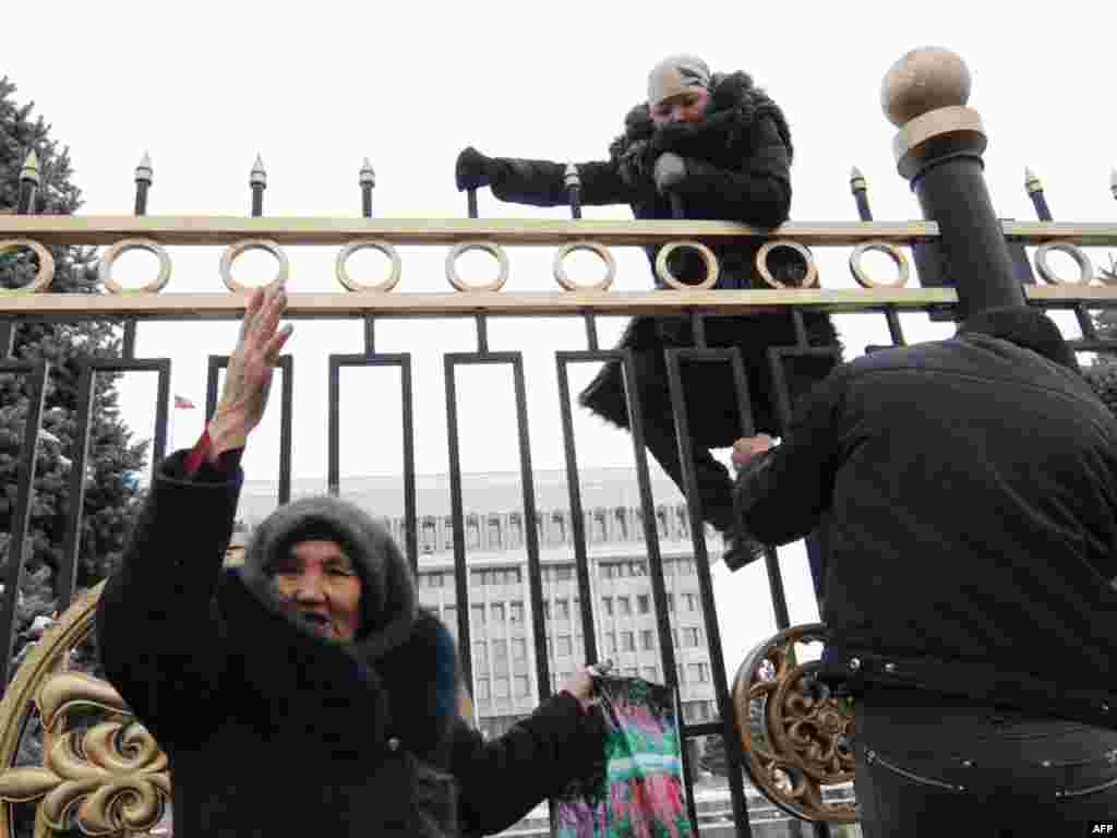 The vendors of the Osh market in the Kyrgyz capital, who recently lost their jobs, try to cross the fence of the government headquarters in Bishkek on March 17. Some 200 protesters gathered in central Bishkek to demand the resignation of the mayor after some of their stalls were removed overnight. Photo by Vyacheslav Oseledko for AFP