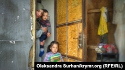 Дети и жена Османа Арифмеметова возле двери, выбитой при обыске