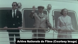 23 august 1984. Nicu Ceaușescu (stânga), Elena Ceaușescu (centru) și Nicolae Ceaușescu (dreapta) salută mulțimea de la bordul unui vas care traversează Canalul Dunăre-Marea Neagră.
