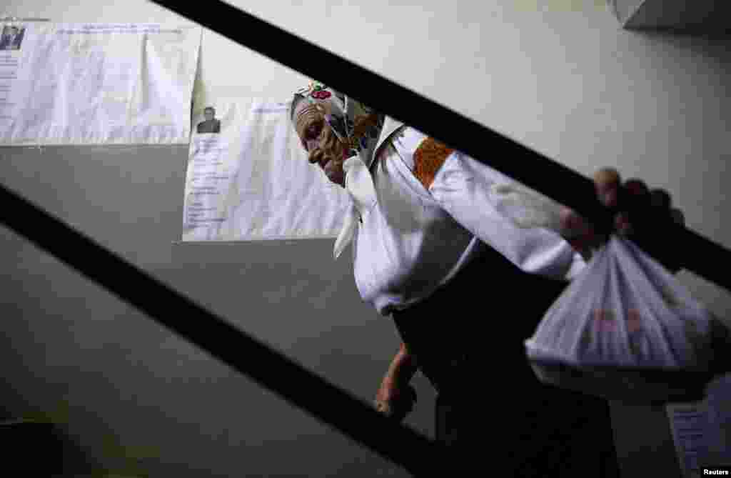 A woman passes lists of candidates during voting in the presidential election at a polling station in the village of Kosmach in the Ivano-Frankivsk region of western Ukraine on May 25. (Reuters/Kacper Pempel)