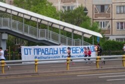 Алматы марафоны кезінде жол жиегінде ілініп тұрған "Шындықтан қашып құтылмайсың" деген жазуы бар плакат. 21 сәуір 2019 жыл.