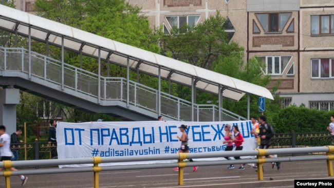 Люди, бегущие вдоль баннера с надписью: «От правды не убежишь». Алматы, 21 апреля 2019 года.