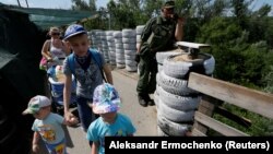 Local residents cross a damaged bridge at the checkpoint located on the contact line between separatist and Ukrainian troops in the settlement of Stanytsia Luhanska on June 9.