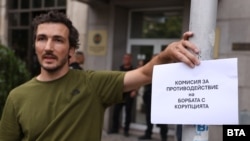 Протестиращ в София пред сградата на Комисията за противодействие на корупцията с надпис "Комисия за противодействие на борбата с корупцията"