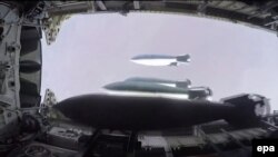 На кадре из видео, опубликованном на сайте министерства обороны России, — сброс снарядов с бомбардировщика Ту-22М3 предположительно над сирийским городом Дэйр аль-Заур.